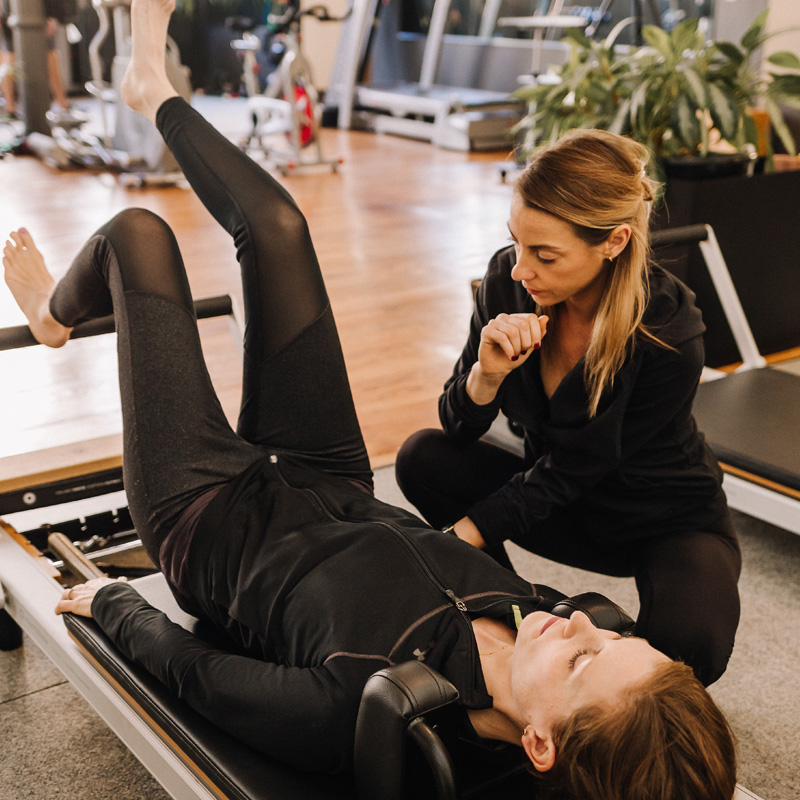 A Sanctuary Body pilates instructor guides her client's exercise