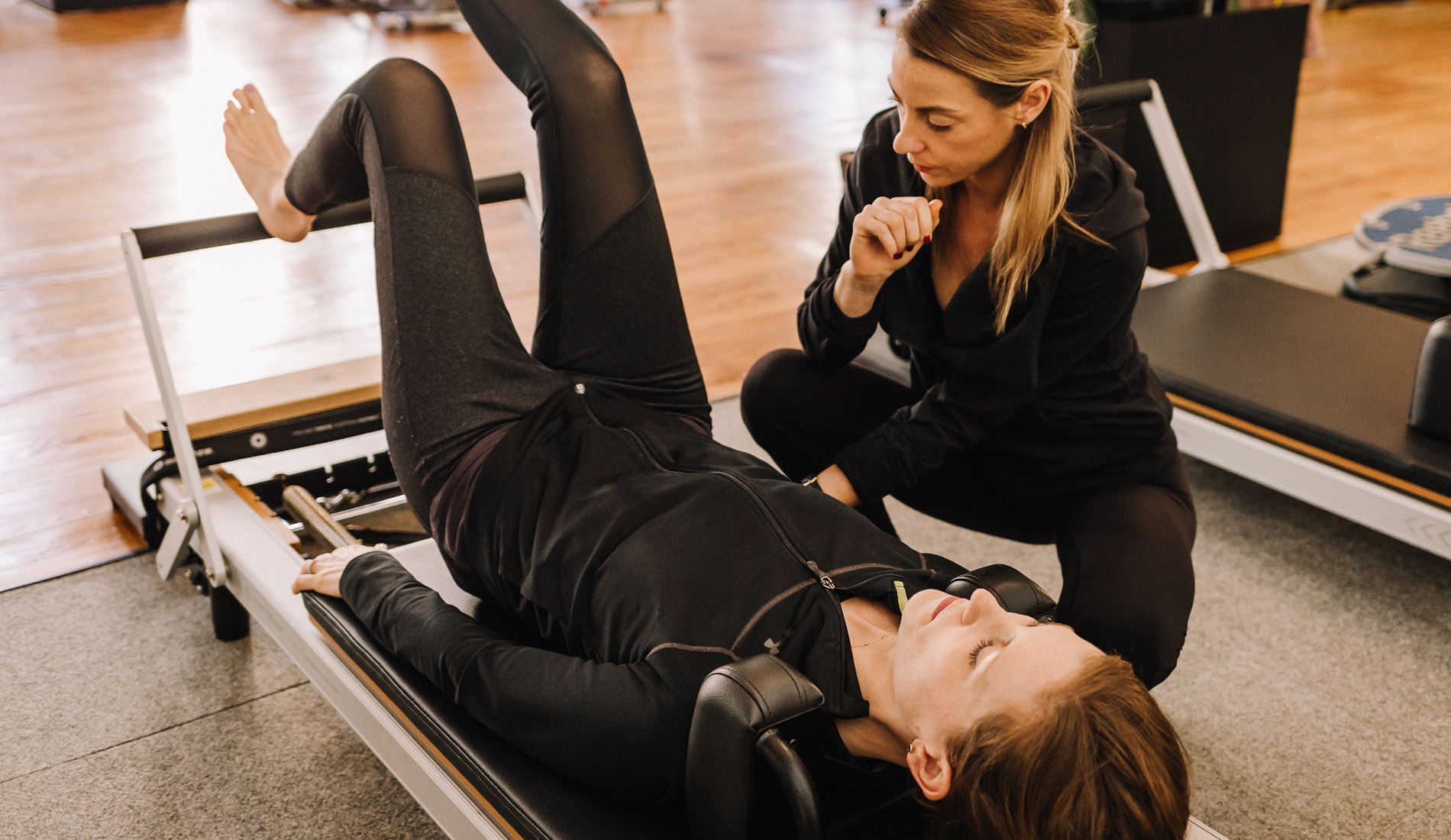 A Sanctuary Body pilates instructor guides her client's exercise
