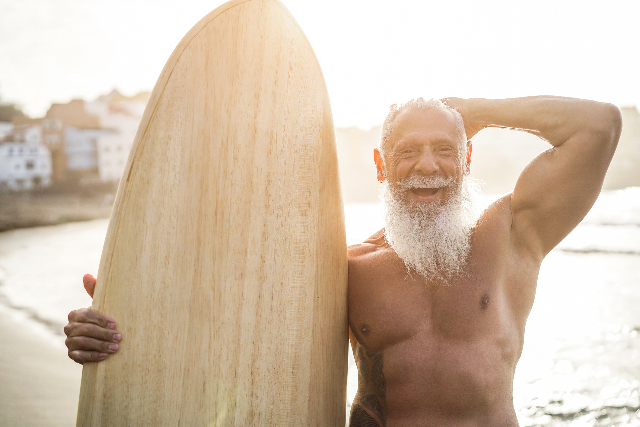 Fit senior with surfboard on the beach.